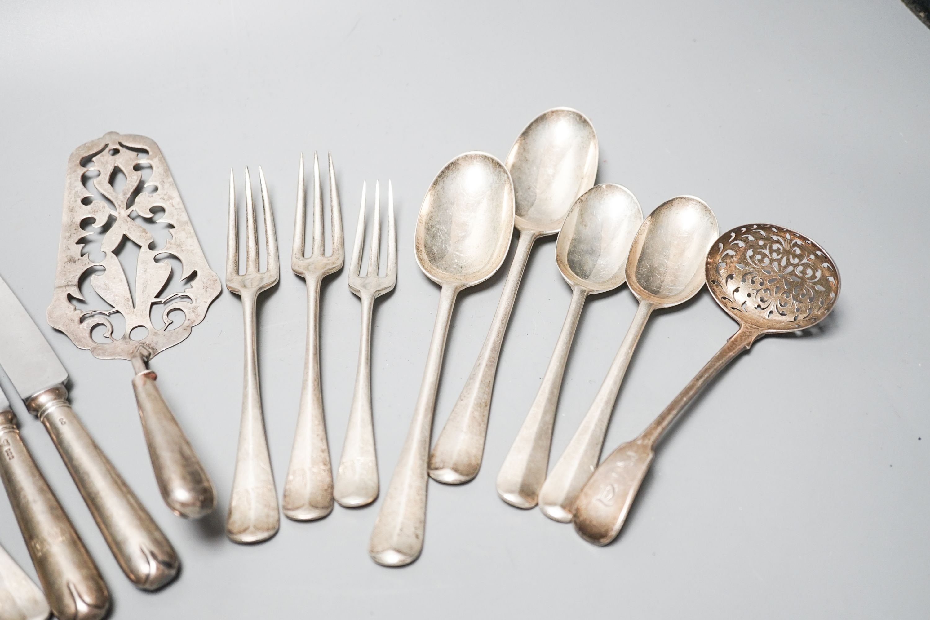 Mixed flatware including a Georgian silver sifter spoon, white metal cake slice, silver three pronged forks etc.